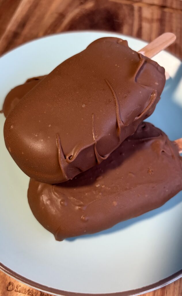 Primo piano di gelati a stecco fatti in casa con copertura di cioccolato al latte