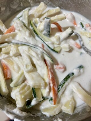Zucchine carote e patate immerse nella pastella per tempura