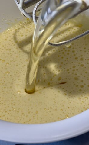 Uova e zucchero montati nella ciotola con l'olio di semi aggiunto all'impasto della ciambella al cacao