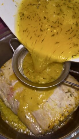 Succo d’arancia filtrato sulla carne di maiale durante la preparazione dell’arista all’arancia.