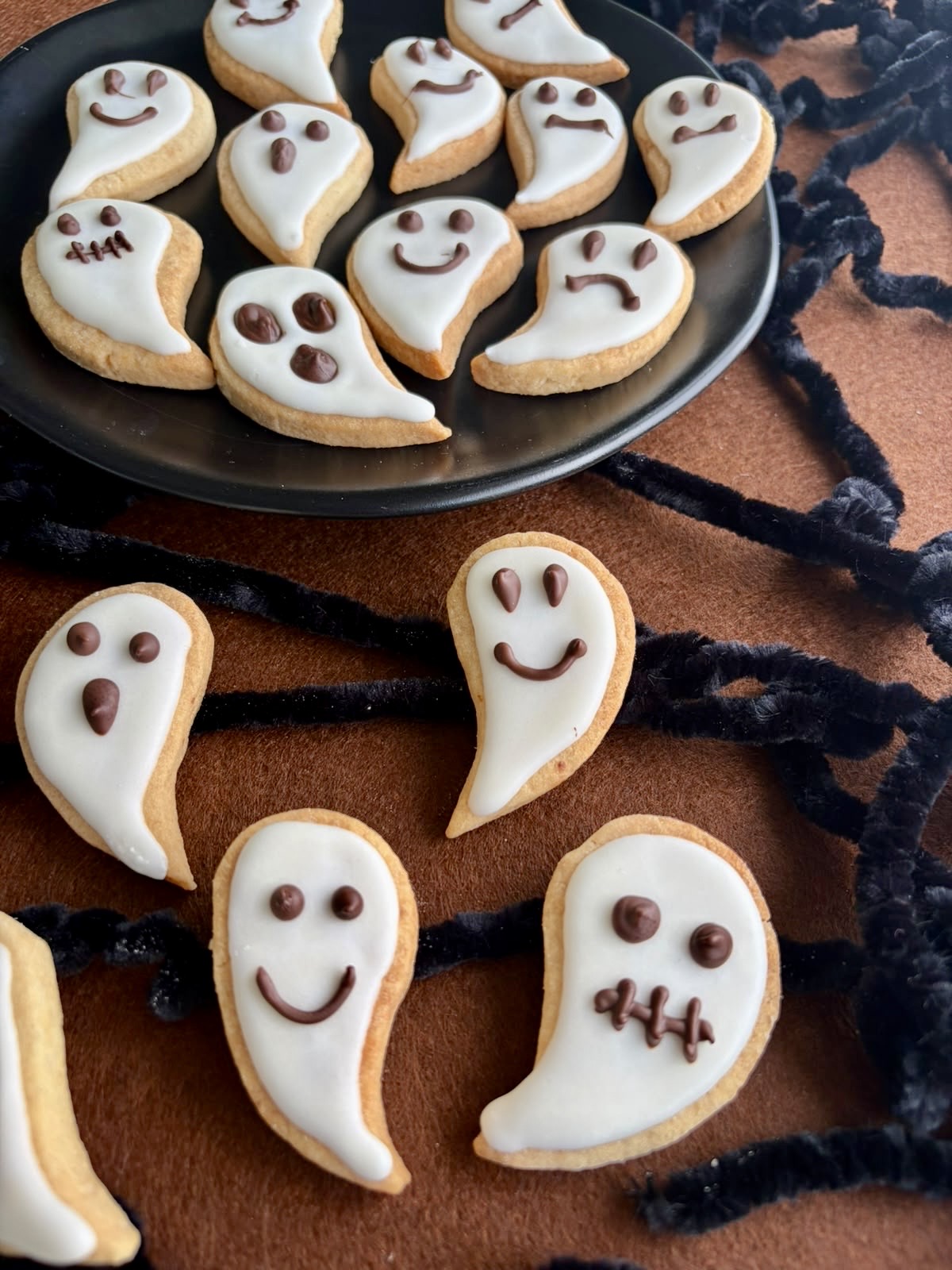 Primo piano di biscotti fantasma di Halloween con ghiaccia bianca e faccine sorridenti e spaventate al cioccolato.