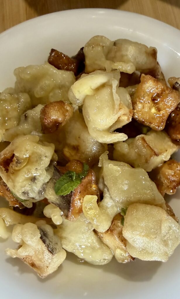 Melanzane in pastella fritte e condite con salsa agrodolce e foglioline di menta.