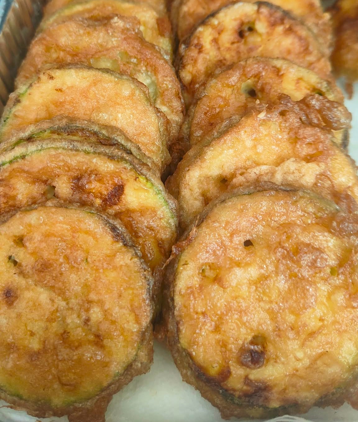 Un piatto di zucchine fritte alla coreana dorate e croccanti con una ciotolina di salsa di soia.