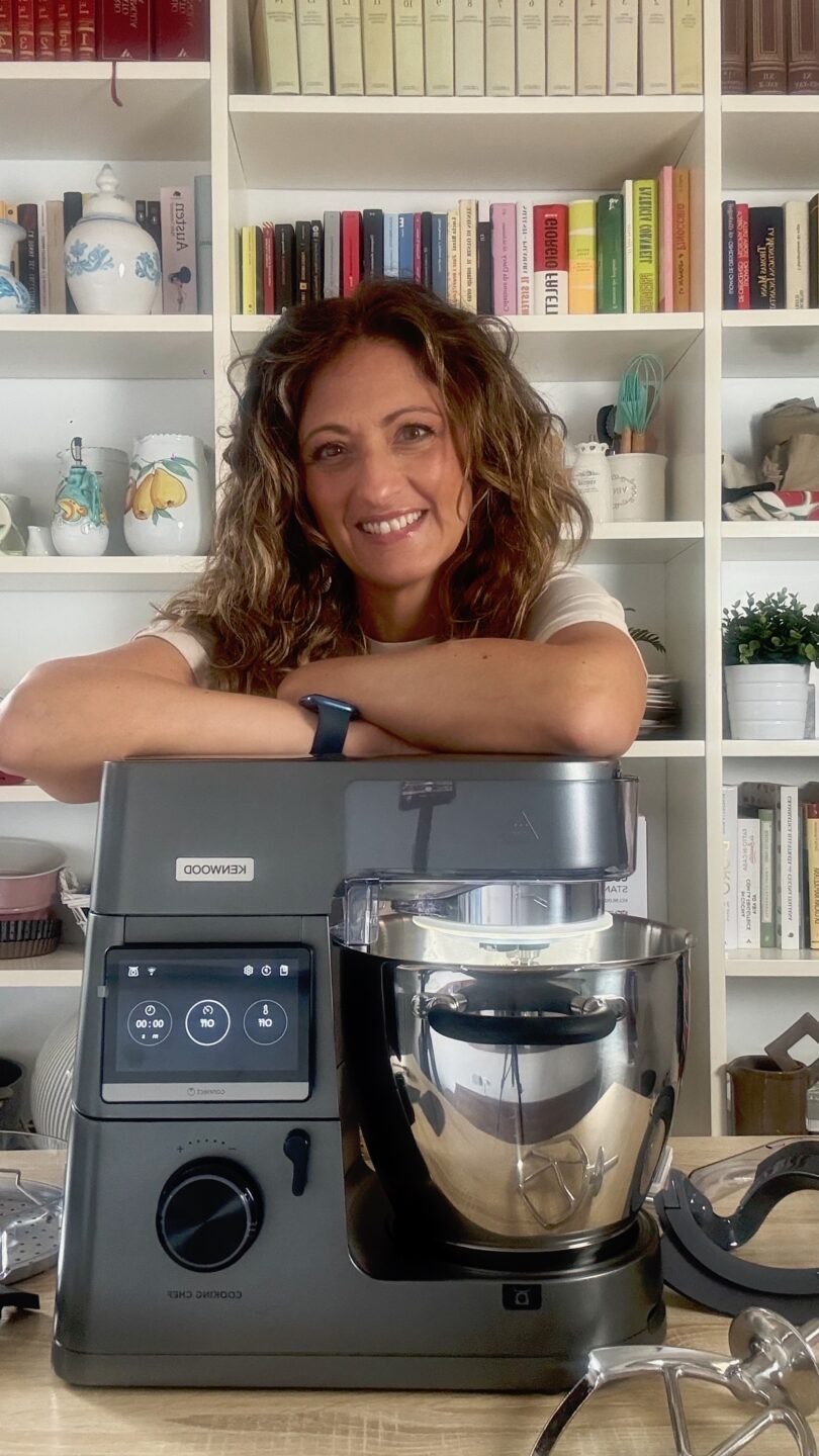Food blogger di Millegrammi sorridente in cucina accanto al robot da cucina Kenwood Cooking Chef XL su sfondo chiaro