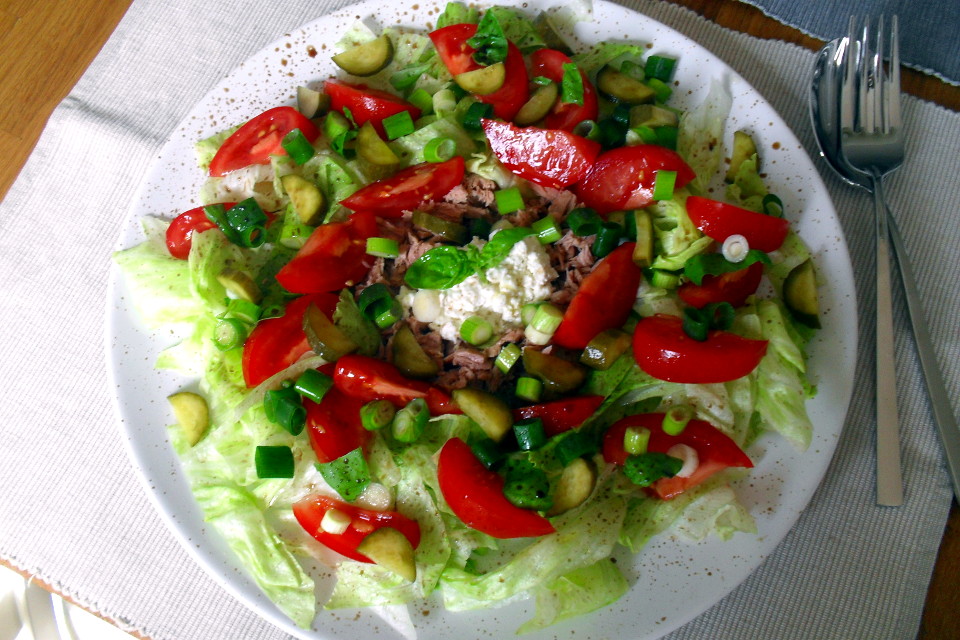Insalata tonno e fiocchi di latte servita su un piatto bianco rotondo accanto a delle posate