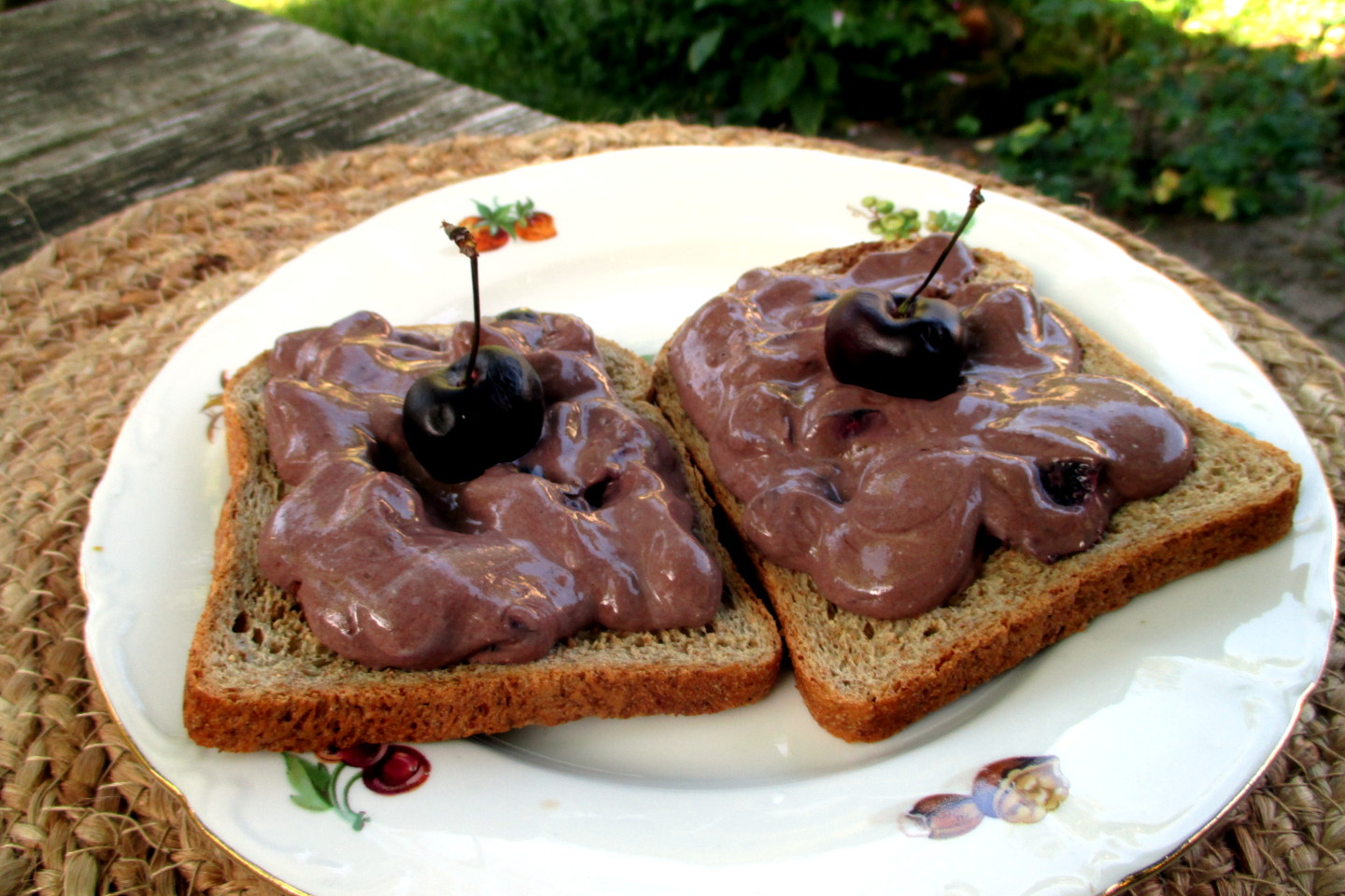 Fette di pane tostato caldo farcite con crema leggera di yogurt al cioccolato e ciliegie fresche a pezzi.