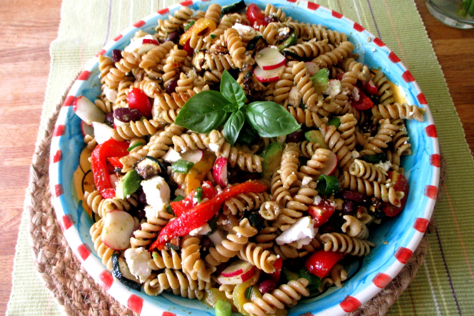Un piatto ricco di insalata di pasta fredda alla messicana con verdure grigliate, fagioli e avocado visto di lato