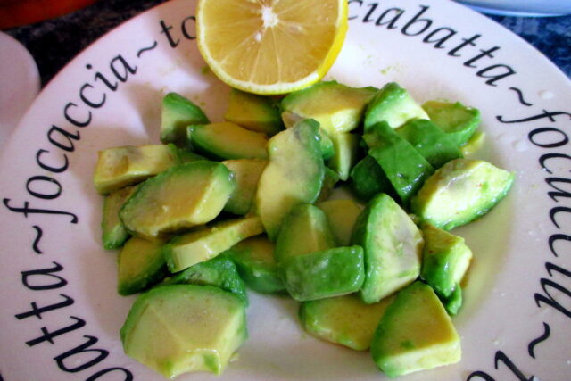 Cubetti di avocado fresco conditi con succo di limone in un piatto di ceramica con scritte sul bordo