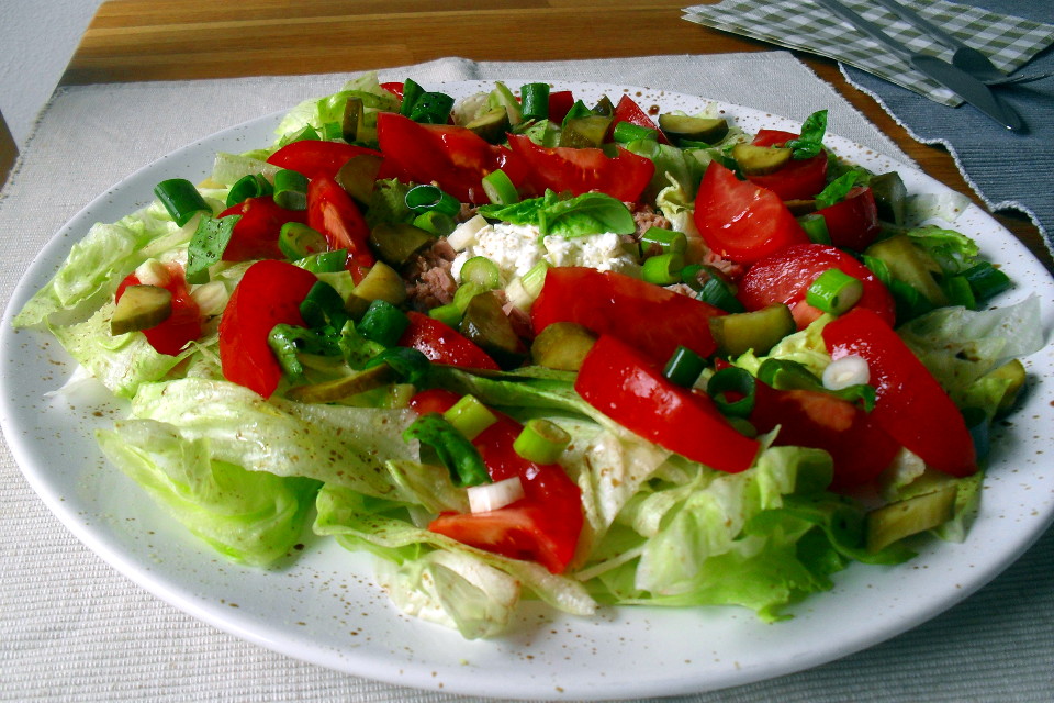 Insalata tonno e fiocchi di latte in un piatto piano bianco appoggiato su una tovaglietta chiara