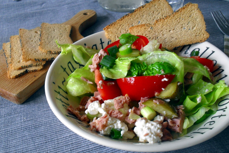 Preparazione insalata tonno e fiocchi di latte: porzione in ciotola decorata accompagnata da crostini melba toast su tagliere
