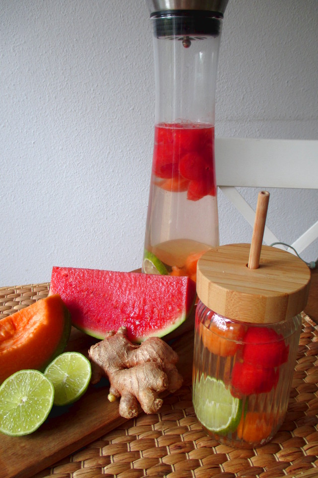Bevanda depurativa anguria e melone con radice di zenzero fresco, lime e fette di frutta sul tagliere di legno