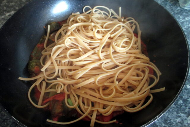 Pasta con friggitelli e pomodorini, linguine versate in padella con il sugo