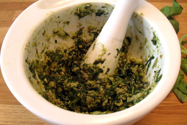 Preparazione pesto di basilico light: foglie di basilico e pinoli parzialmente pestati nel mortaio