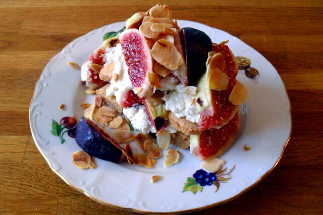 Tiramisù fichi e ricotta con savoiardi bagnati al caffè e fichi freschi in evidenza su un tavolo di legno