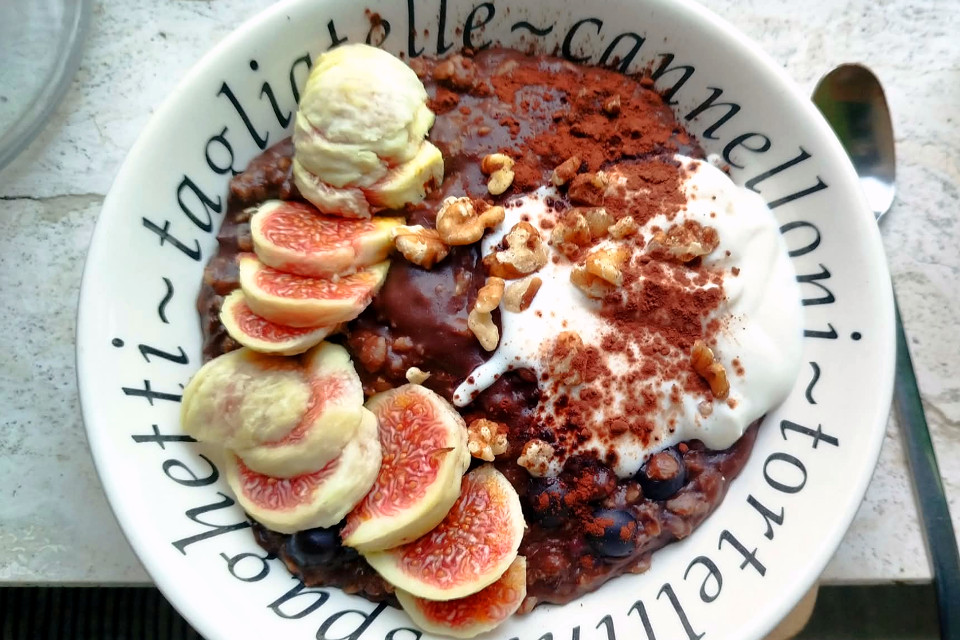 Ciotola di porridge al cacao con fichi freschi, yogurt, noci e cacao in polvere