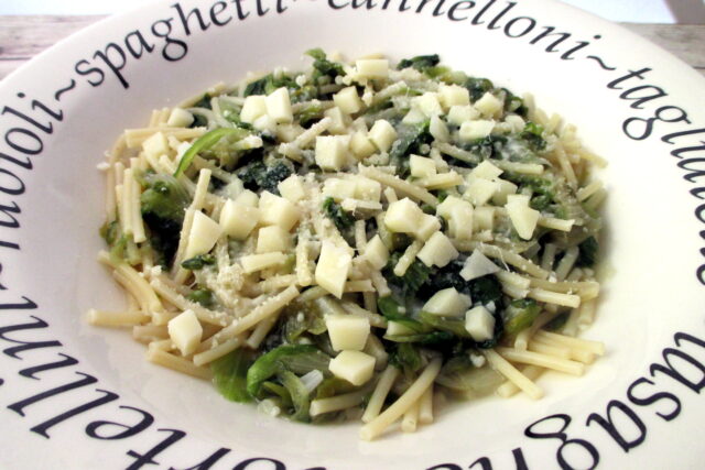 Spaghetti con scarola nel piatto con parmigiano e formaggio a dadini