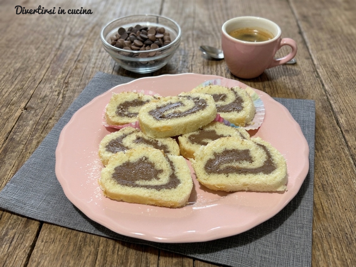 Rotolo dolce con crema alla Nutella e mascarpone servito a fette su un piatto rosa con gocce di cioccolato e una tazzina di caffè