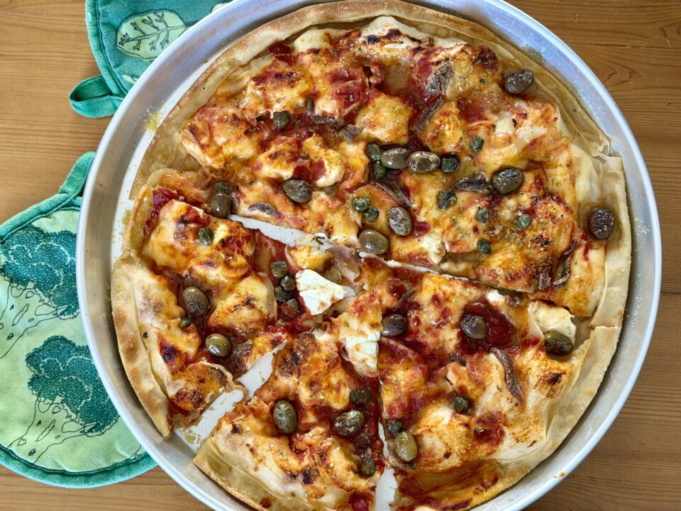 Pizzata ligure: focaccia sottile con stracchino, pomodoro, olive e acciughe