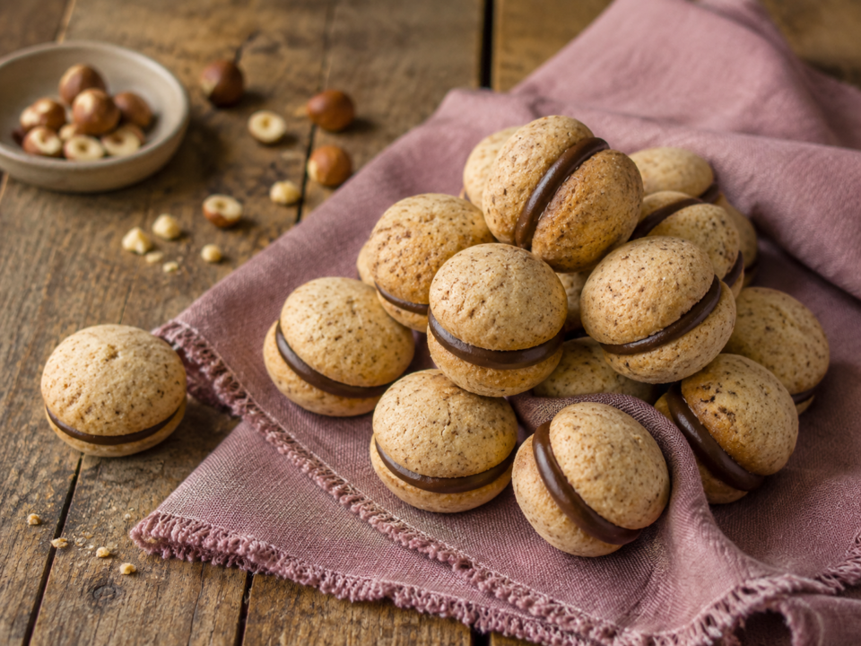 Baci di dama fatti in casa con mandorle e nocciole: biscotti friabili uniti da crema al cioccolato, facili da preparare e perfetti da regalare.