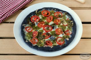Pizza nera con pesto e pomodorini