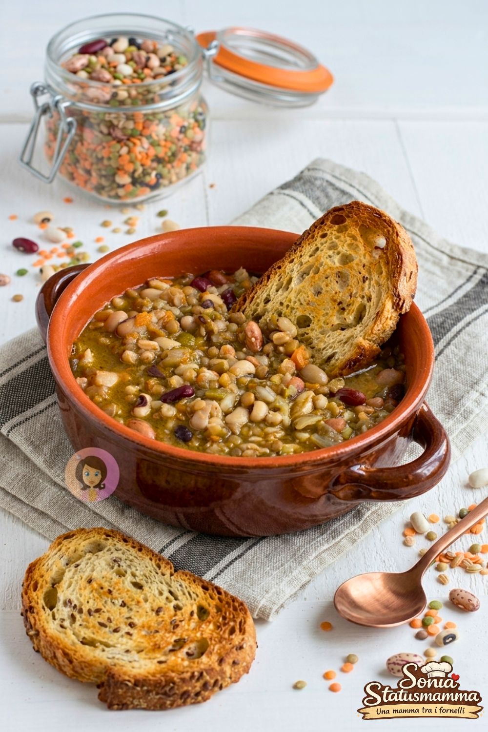 Zuppa di legumi mista con ceci, fagioli e lenticchie servita in una ciotola di terracotta con fette di pane abbrustolito orizzontale verticale