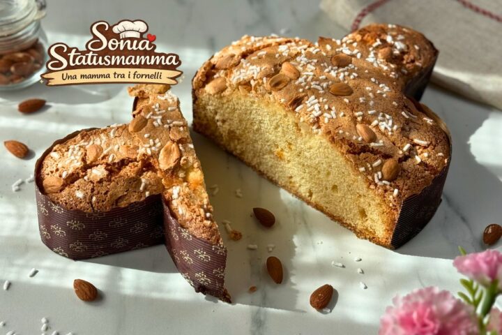 Colomba veloce mandorlata su piano di marmo bianco con granella di zucchero e mandorle intere, ricetta di Statusmamma.