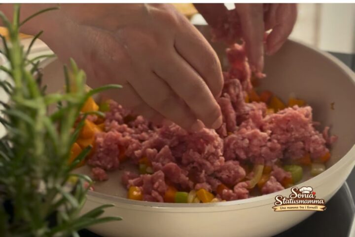 Trito di sedano, carota e cipolla che soffrigge in padella con carne