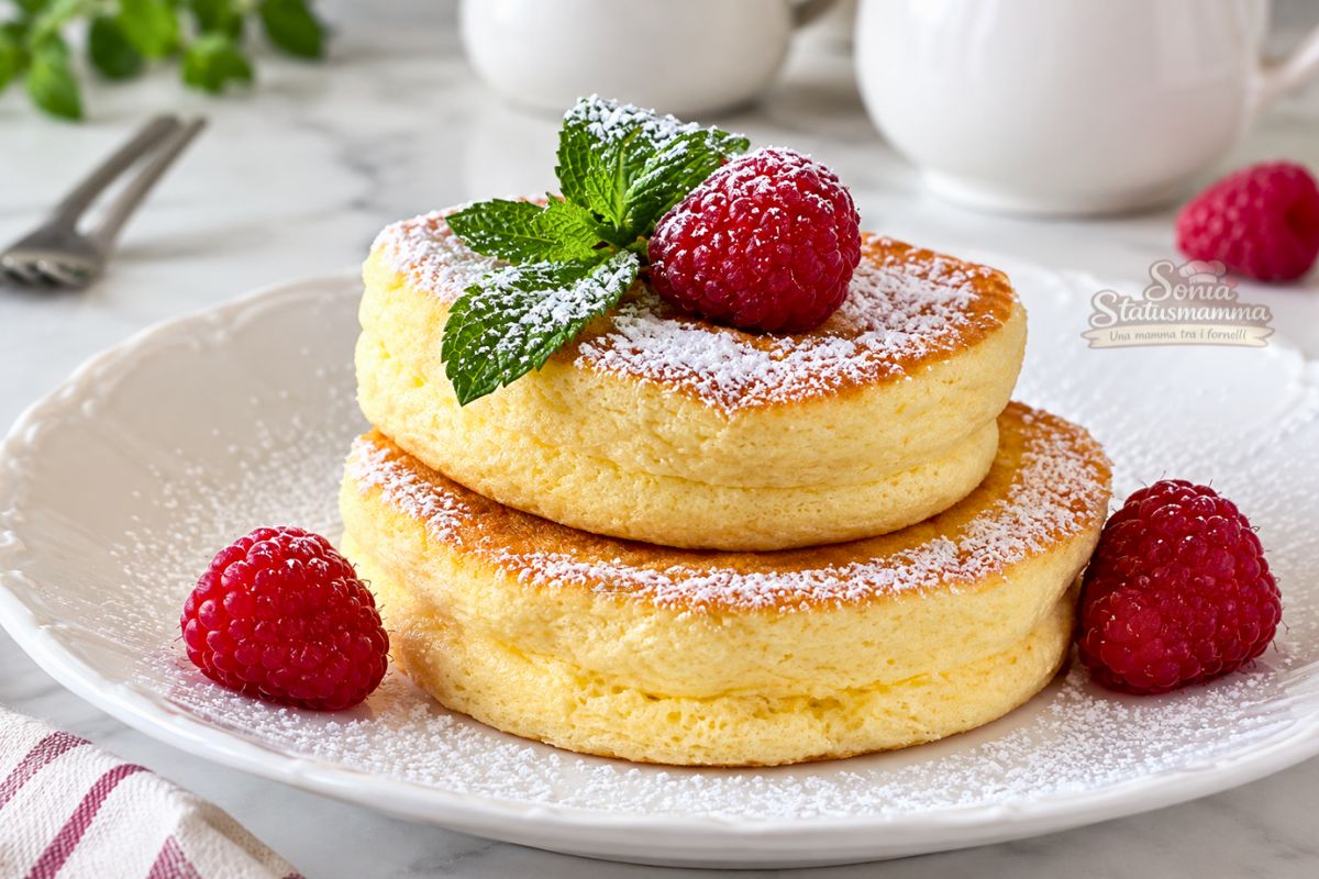 Japanese pancake soffici e alti con zucchero a velo, lamponi e menta su un piatto bianco
