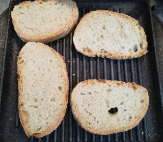 Crostoni di cavolo nero: Fette di pane casereccio che abbrustoliscono sopra una graticola sul gas