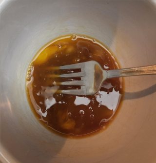 uova con salsa di soia in una tazza che si mescolano con una forchetta