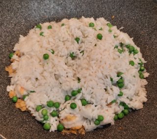 riso e piselli aggiunti nel wok